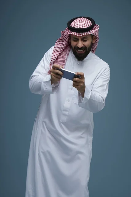 Saudi Man in Traditional Thobe Playing Mobile Game