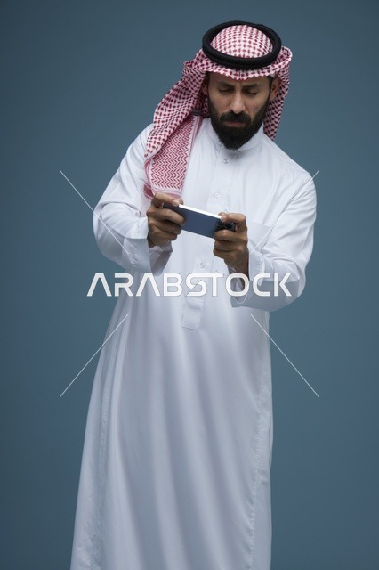 رجل سعودي يلعب ألعاب الجوال باستخدام الهاتف الذكي