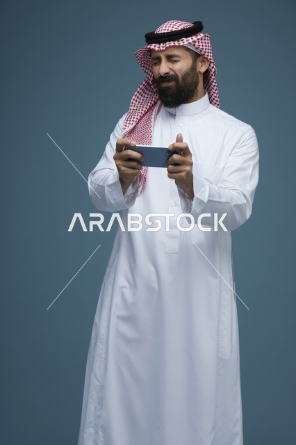 Saudi Man Playing Mobile Games on Smartphone in Studio