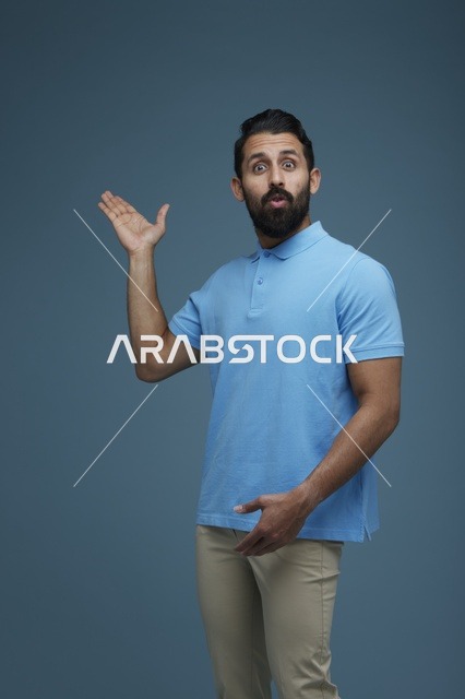 رجل سعودي مندهش يشير بيديه خلفية زرقاء