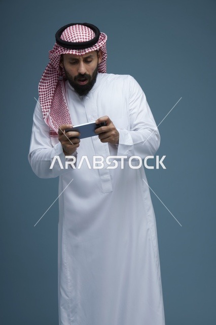 رجل سعودي يلعب بهاتفه الذكي في الاستوديو