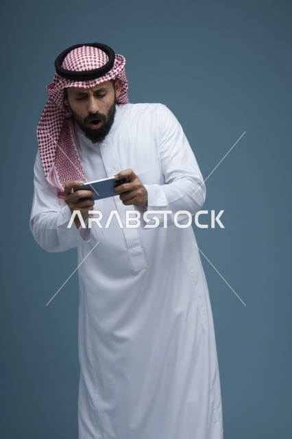 رجل سعودي يلعب ألعاب الفيديو على الهاتف الذكي