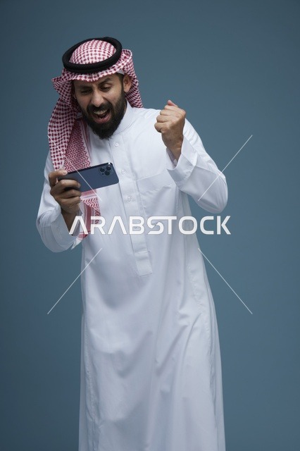 رجل سعودي يحتفل بالفوز بلعبة على الهاتف الذكي