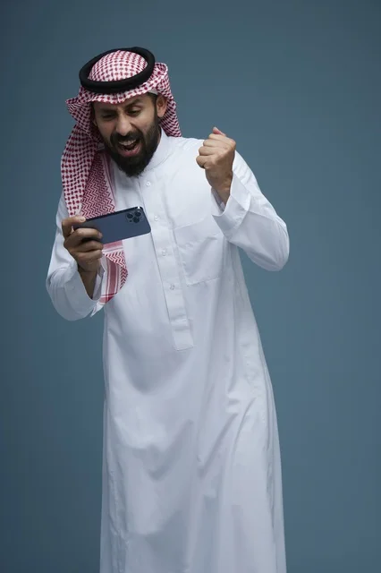 Saudi Man Celebrating Mobile Game Victory on Smartphone