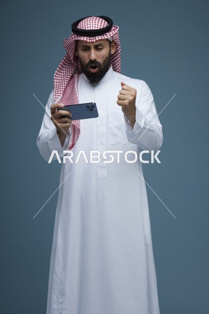 رجل سعودي يلعب ألعاب الجوال على الهاتف الذكي