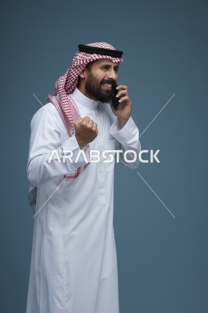 رجل سعودي بالزي التقليدي يحتفل بالنجاح عبر الجوال