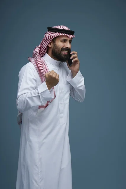 رجل سعودي بالزي التقليدي يحتفل بالنجاح عبر الجوال