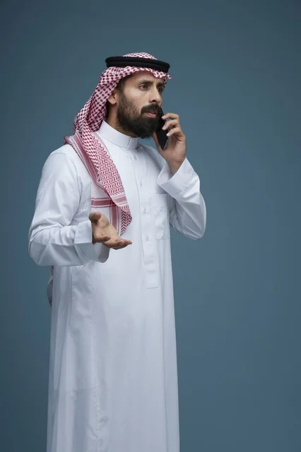 Saudi Man in Traditional Thobe Talking on Smartphone