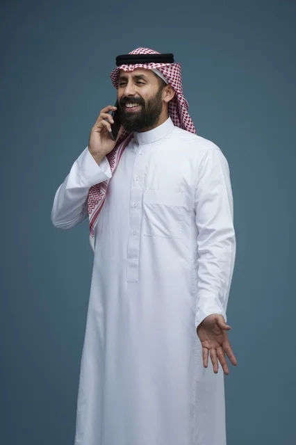 رجل سعودي يرتدي الثوب التقليدي يتحدث بالهاتف الذكي