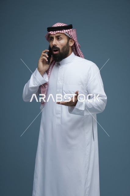 رجل سعودي مصدوم يتحدث بالهاتف الذكي في الاستوديو