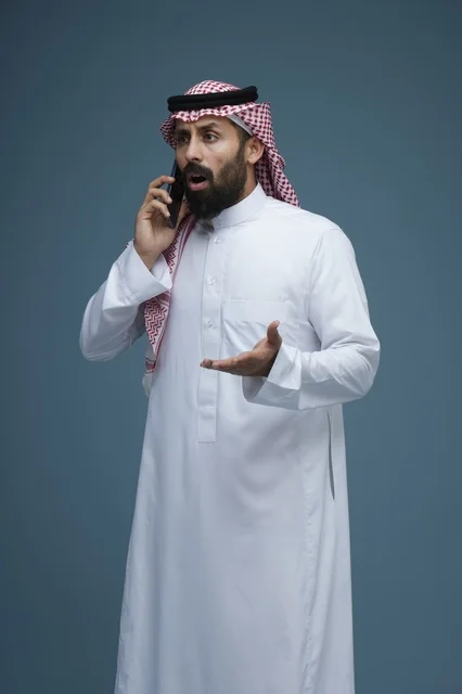 رجل سعودي مصدوم يتحدث بالهاتف الذكي في الاستوديو