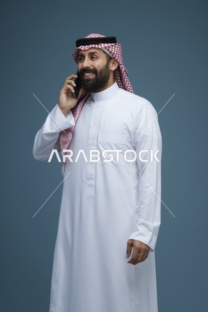 رجل سعودي بالثوب يتحدث بالهاتف الذكي في الاستوديو