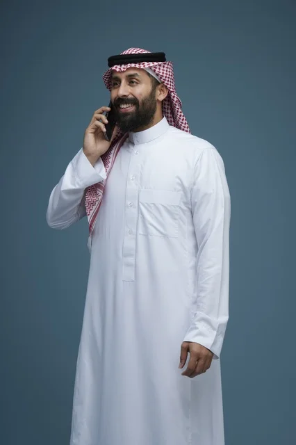 رجل سعودي بالثوب يتحدث بالهاتف الذكي في الاستوديو