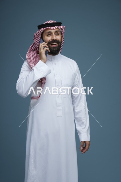 رجل سعودي يتحدث عبر الجوال بالثوب والشماغ التقليدي