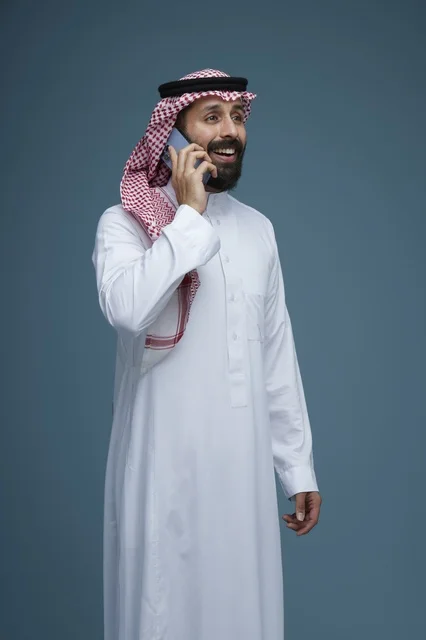 Saudi Man in Traditional Attire Talking on Smartphone