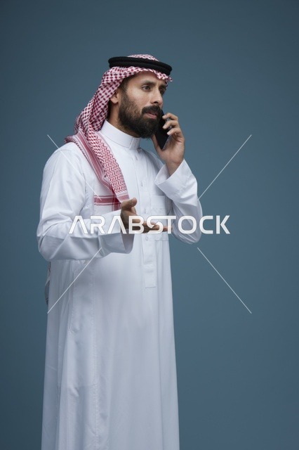 رجل سعودي بالثوب والشماغ يتحدث عبر الهاتف الذكي