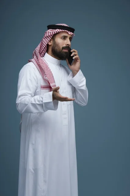 رجل سعودي بالثوب والشماغ يتحدث عبر الهاتف الذكي