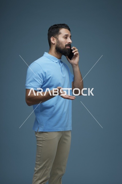 رجل سعودي يتحدث بالهاتف الذكي مرتدياً ملابس كاجوال