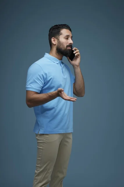 رجل سعودي يتحدث بالهاتف الذكي مرتدياً ملابس كاجوال