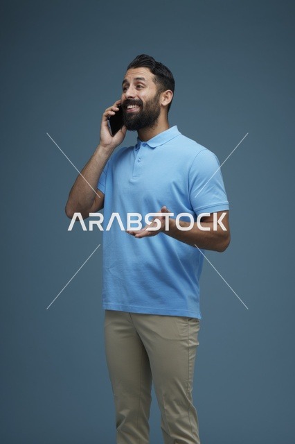 رجل سعودي يتحدث عبر الهاتف الذكي بملابس كاجوال