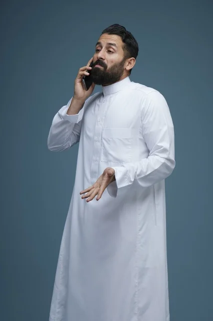 رجل سعودي بالثوب يتحدث عبر الهاتف الذكي في استوديو
