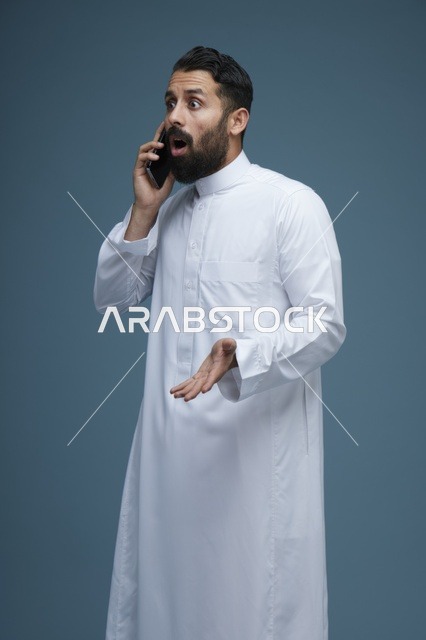 رجل سعودي متفاجئ يتحدث عبر الهاتف الذكي في الاستوديو