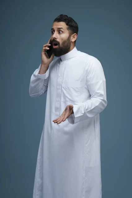 رجل سعودي متفاجئ يتحدث عبر الهاتف الذكي في الاستوديو