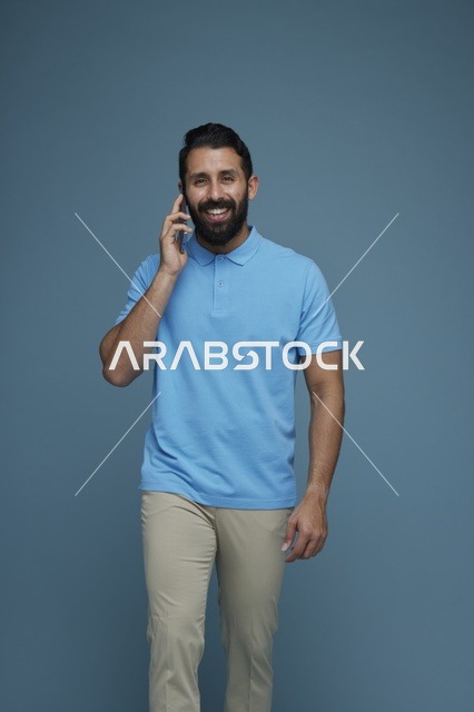 رجل سعودي يتحدث بالهاتف الذكي خلفية زرقاء