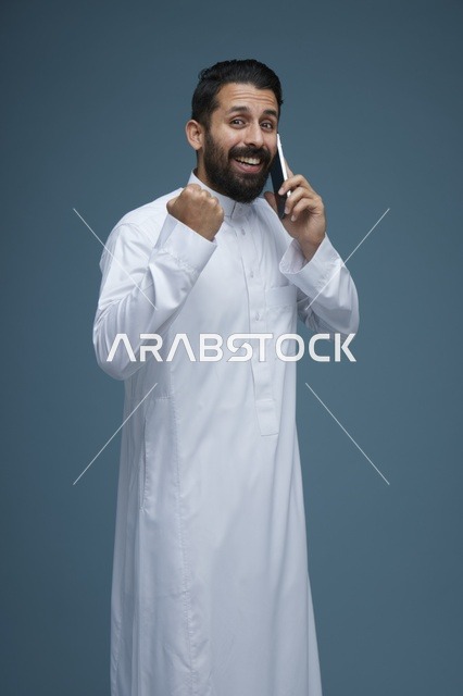 رجل سعودي يتحدث بالهاتف الذكي ويحتفل بالنجاح في استوديو
