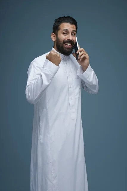 رجل سعودي يتحدث بالهاتف الذكي ويحتفل بالنجاح في استوديو