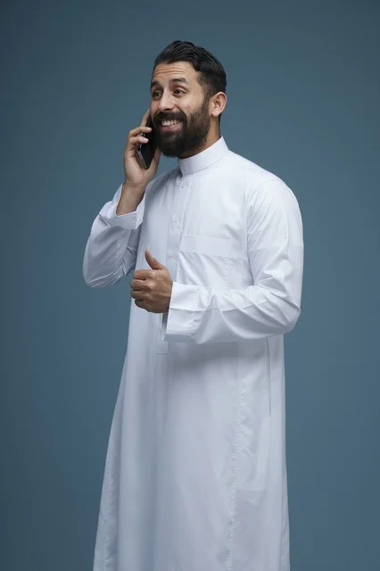 رجل سعودي مبتسم يتحدث عبر الهاتف الذكي في الاستوديو