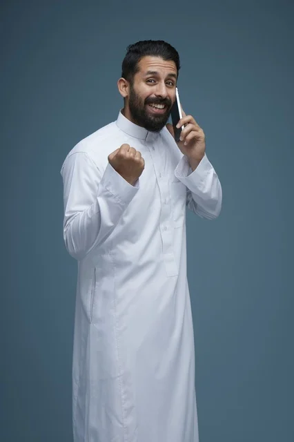 Smiling Saudi Man Celebrating Success on Smartphone Call