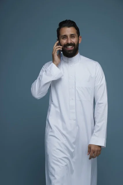 رجل سعودي مبتسم يتحدث بالهاتف الذكي في الاستوديو