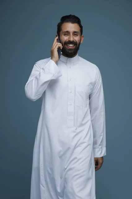 رجل سعودي بالثوب الأبيض يتحدث بالهاتف الذكي