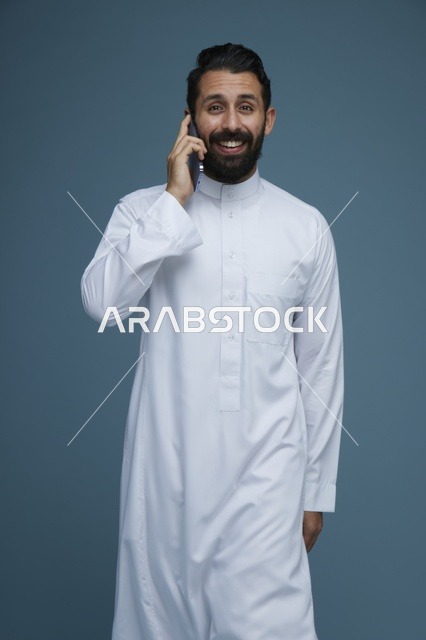 رجل سعودي بالثوب التقليدي يتحدث عبر الهاتف الذكي
