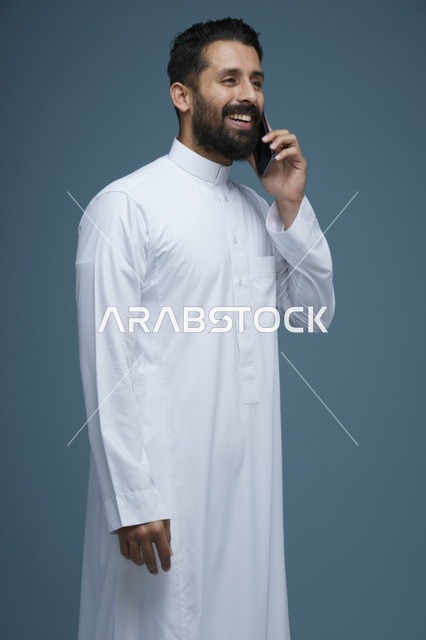 رجل سعودي بالثوب يتحدث بالهاتف الذكي في الاستوديو