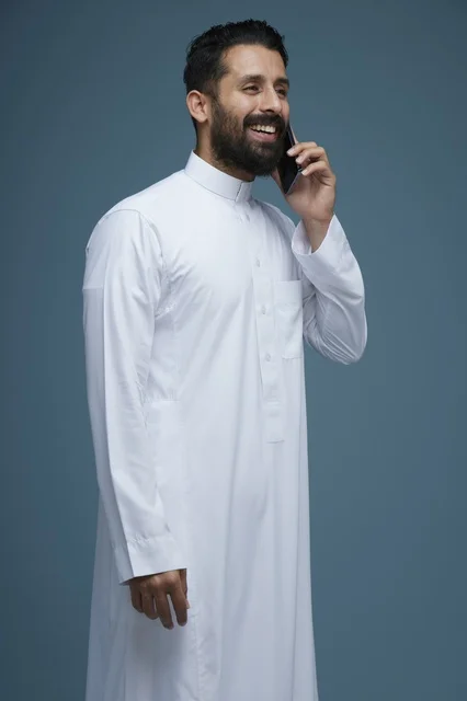 رجل سعودي بالثوب يتحدث بالهاتف الذكي في الاستوديو