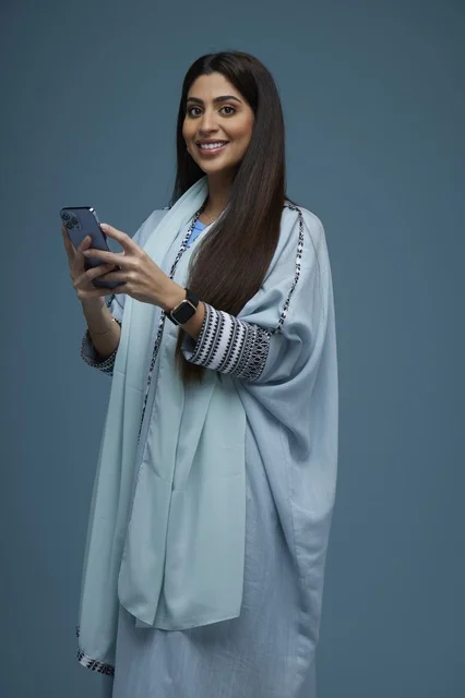 Smiling Saudi Woman Using Smartphone on Blue Background