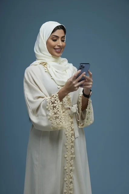 Saudi Woman in Cream Abaya Using Smartphone in Studio