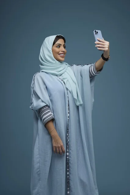 امرأة سعودية بالعباءة تلتقط صورة سيلفي بالجوال