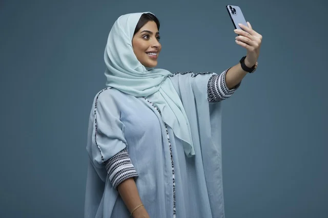 Saudi Woman Taking Smartphone Selfie on Blue Background