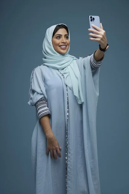 امرأة سعودية تلتقط صورة سيلفي بالهاتف في الاستوديو