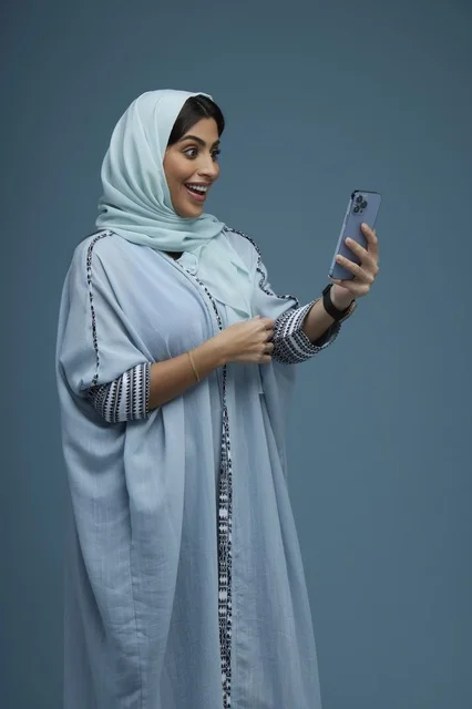 امرأة سعودية تستخدم الهاتف الذكي بتعبيرات مندهشة