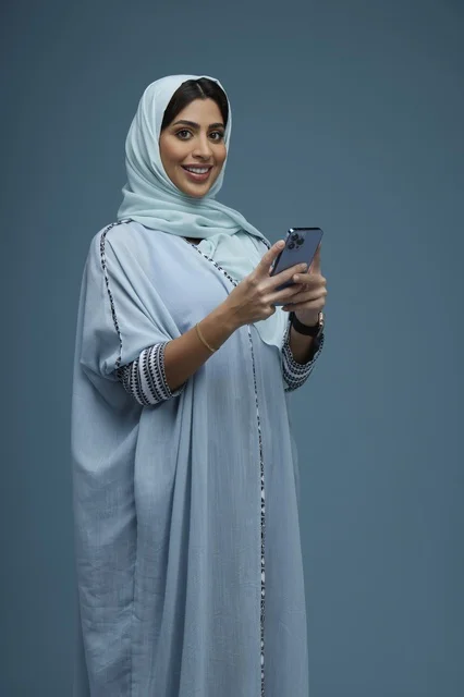Saudi Woman Portrait with Smartphone on Blue Background