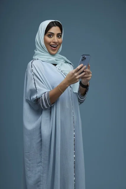 امرأة سعودية تحمل هاتف ذكي في استوديو