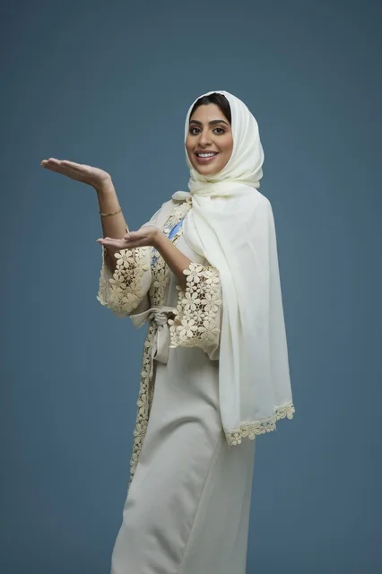 Saudi Woman in White Abaya Gesturing on Blue Background