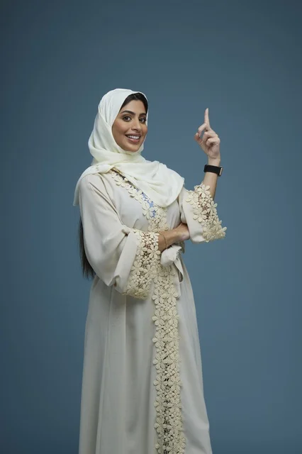 Saudi Woman in White Abaya Pointing Up on Blue Background