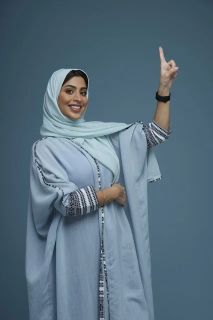 Saudi Woman Pointing Upward in Light Blue Abaya