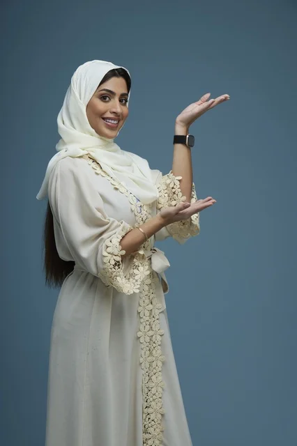 امرأة سعودية بالحجاب تشير بيدها في الاستوديو