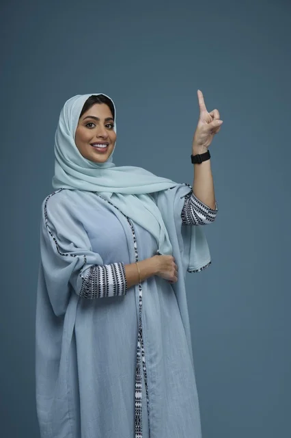Saudi Woman Pointing Upwards on Blue Background